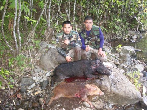 1991 Ford Bronco - Hunters pose with their wild boar kill by a stream in a wooded area.