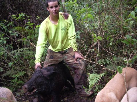 1991 Ford Bronco - A hunter poses with his wild boar catch in a dense forest environment.