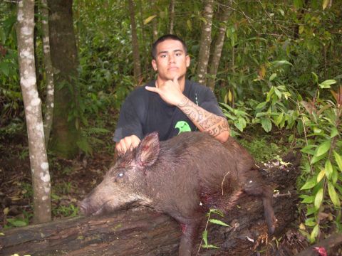 1991 Ford Bronco - A hunter poses with a wild boar he has caught, resting on a fallen log in a wooded area.