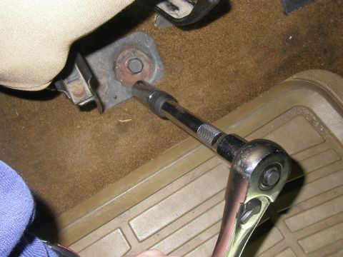 1990 Ford Bronco - A socket wrench is used to remove a seat bolt inside a vehicle's interior.