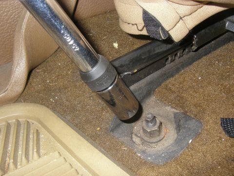 1990 Ford Bronco - Using a socket wrench to loosen a seat mounting bolt.