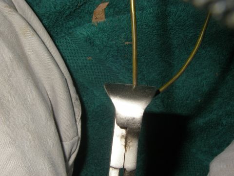 1990 Ford Bronco - A close-up view of a metal component with brass rods, set against a textured green background and a folded grey fabric.