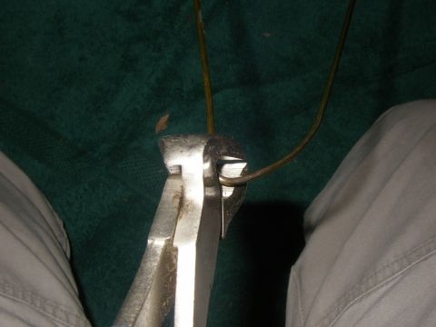 1990 Ford Bronco - Close-up of pliers gripping and bending a wire, possibly for a repair.