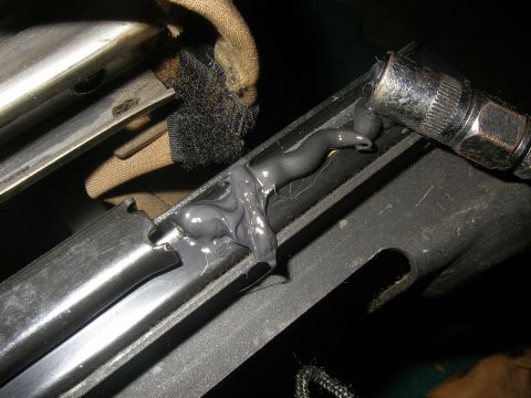1990 Ford Bronco - Applying lubricant to a metal track with a grease gun.
