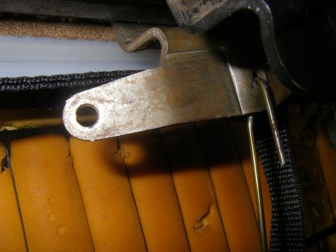 1990 Ford Bronco - Close-up of a vehicle's seat mechanism, showing a rusty bracket and exposed foam padding.