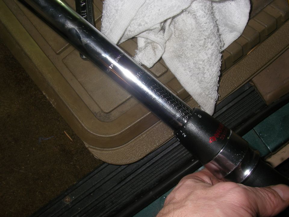 Close-up of a torque wrench with visible markings, held by a hand inside a vehicle