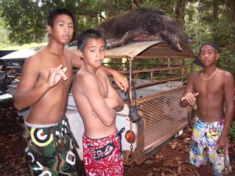 1991 Ford Bronco - Three young men pose with a wild boar on a trailer in a wooded area.