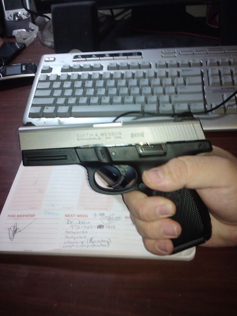 1989 Ford Bronco - A hand grips a Smith & Wesson pistol, obscuring a notepad with handwritten appointments.