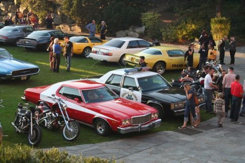1991 Ford Crown Victoria - A gathering of vintage vehicles, including a police car and a red and white coupe, are on display with onlookers.