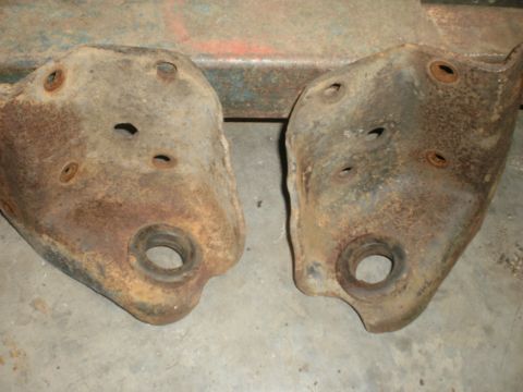 1995 Ford Bronco - Pair of heavily rusted suspension components, likely control arm brackets, shown up close.