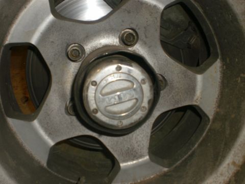 1995 Ford Bronco - A close-up view of a vehicle's wheel hubcap, "4x4" branding and a visible brake rotor.