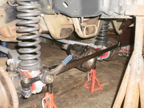 1995 Ford Bronco - The underside of a vehicle is shown with its suspension and axle components supported by jack stands.