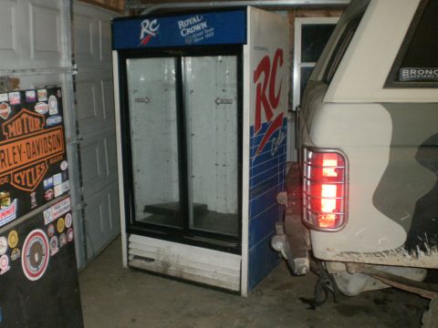1995 Ford Bronco - Vehicle parked next to a commercial refrigerator inside a garage.
