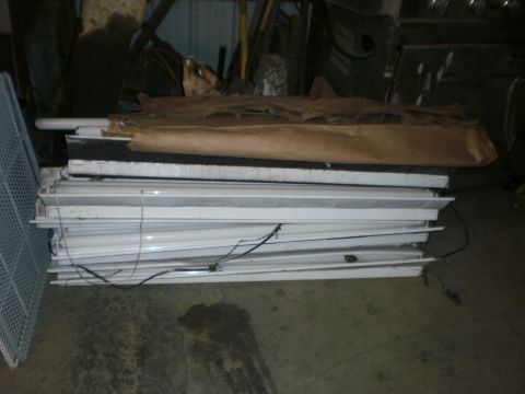 1995 Ford Bronco - A pile of fluorescent light fixtures are stored indoors, some wrapped in brown paper.