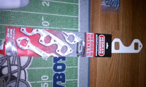 1996 Ford Bronco - Header gaskets are shown with their packaging and branding, placed on a rug with football field markings.