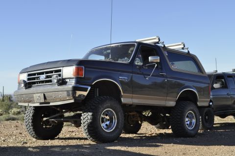 1991 Ford Bronco - A lifted 1992 Ford Bronco with off-road tires is parked outdoors next to another vehicle.