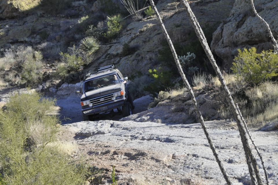 Dark SUV with roof rack navigating a rocky incline