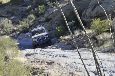 1991 Ford Bronco - SUV navigates a challenging rocky path in a desert environment.