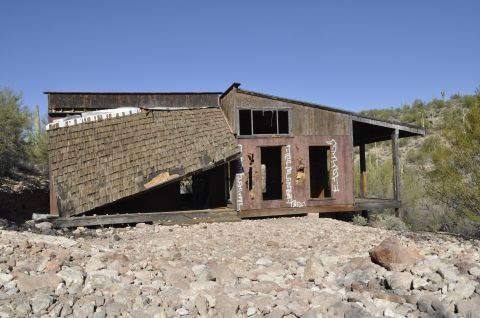1991 Ford Bronco - An old, weathered building stands in ruins, its roof partially caved in and walls marked with spray paint.