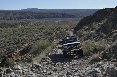 1991 Ford Bronco - A 1991 Ford Bronco navigates a challenging rocky path through a desert landscape.