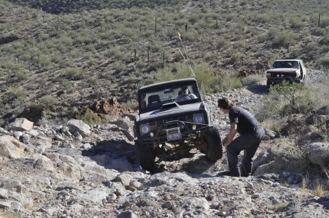 1991 Ford Bronco - Two off-road vehicles tackle a steep, rocky incline in a desert landscape.