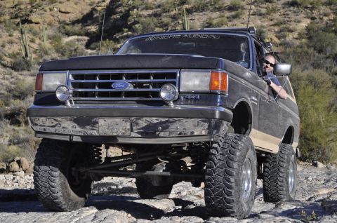 1991 Ford Bronco - This lifted Ford Bronco, likely a 1992 model, navigates a rocky, desert terrain.