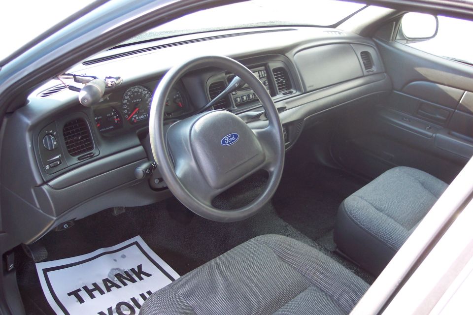 2001 Ford Crown Victoria interior showing dashboard, steering wheel, and seats. 'Thank You' mat on floor