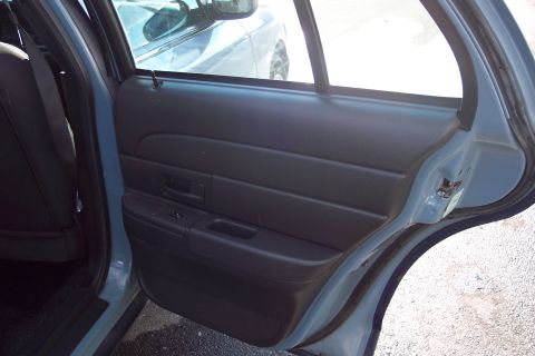2001 Ford Crown Victoria - View of the rear passenger door interior and a reflection of another vehicle in the side mirror.