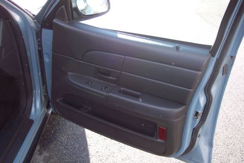 2001 Ford Crown Victoria - Interior view of a car door panel with window controls and a red reflector.