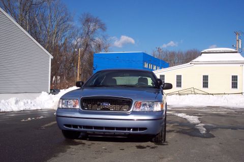 2001 Ford Crown Victoria - A blue 2001 Ford Crown Victoria is parked outside on a sunny day with snow piled up around it.