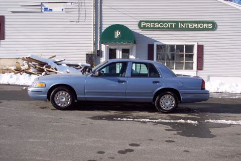 2001 Ford Crown Victoria - A blue 2001 Ford Crown Victoria is parked in front of a building with a sign that reads Prescott Interiors.