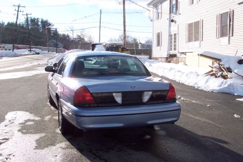 2001 Ford Crown Victoria - Rear view of a light blue 2001 Ford Crown Victoria parked on a wet asphalt surface during winter.
