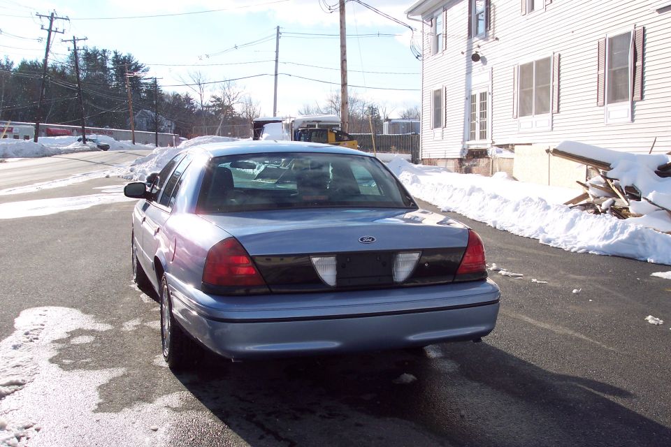 2001 Ford Crown Victoria rear view, light blue paint, parked on asphalt with snow on the sides