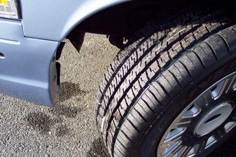 2001 Ford Crown Victoria - Close-up view of a vehicle's tire and fender, with gravel on the ground.