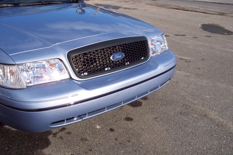 2001 Ford Crown Victoria - The front grille and headlights of a light blue Ford Crown Victoria are visible.