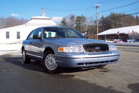 2001 Ford Crown Victoria - A light blue 2001 Ford Crown Victoria is parked outside a building on a sunny day with snow on the ground.