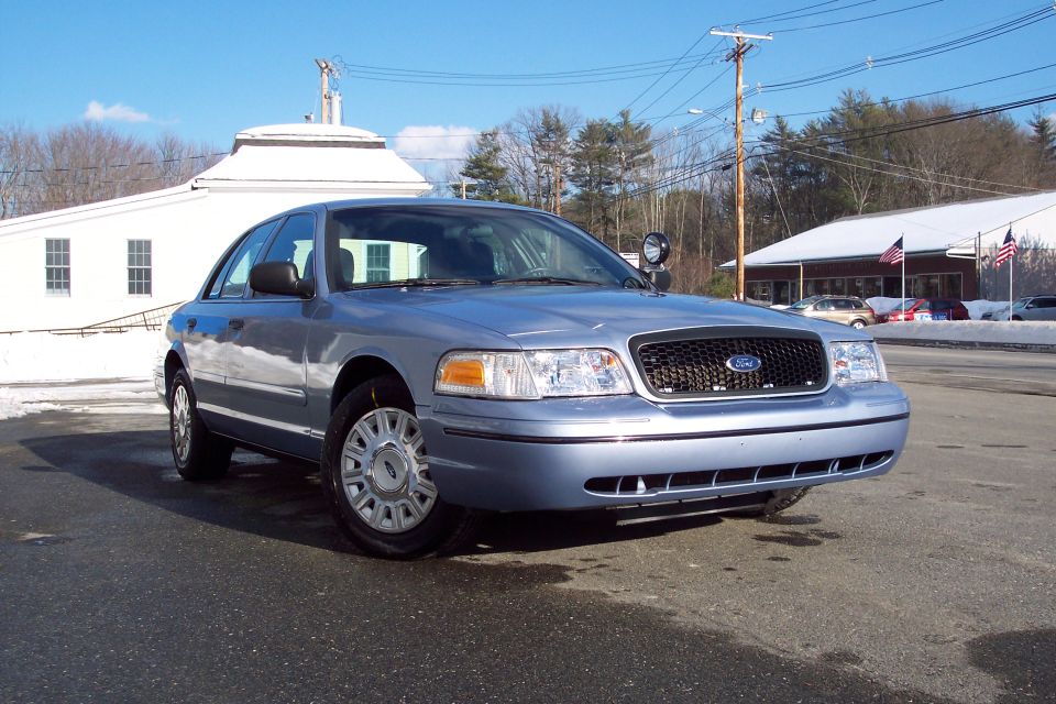 Light blue 2001 Ford Crown Victoria parked on asphalt with snow in the background