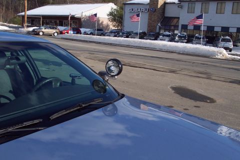 2001 Ford Crown Victoria - A blue police car with a spotlight is parked in front of a Subaru dealership on a snowy day.