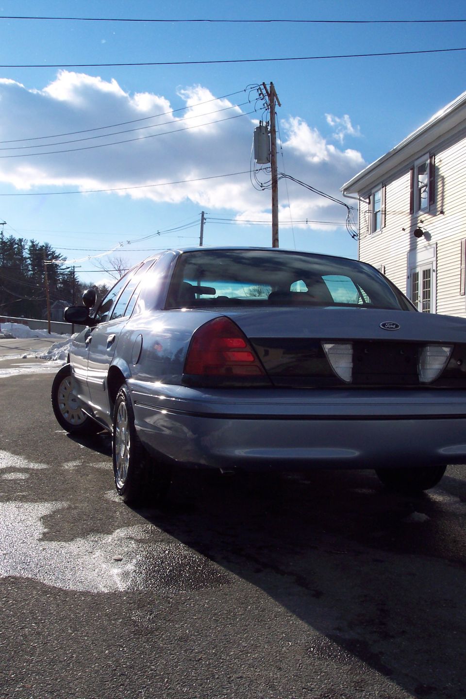 Blue 2001 Ford Crown Victoria, rear view, parked on wet asphalt
