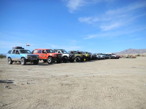 1997 Ford Ranger - A group of modified off-road vehicles are parked in a desert landscape.