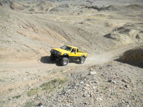 1997 Ford Ranger - Yellow 1997 Ford Ranger navigates a challenging off-road course in a desert landscape.