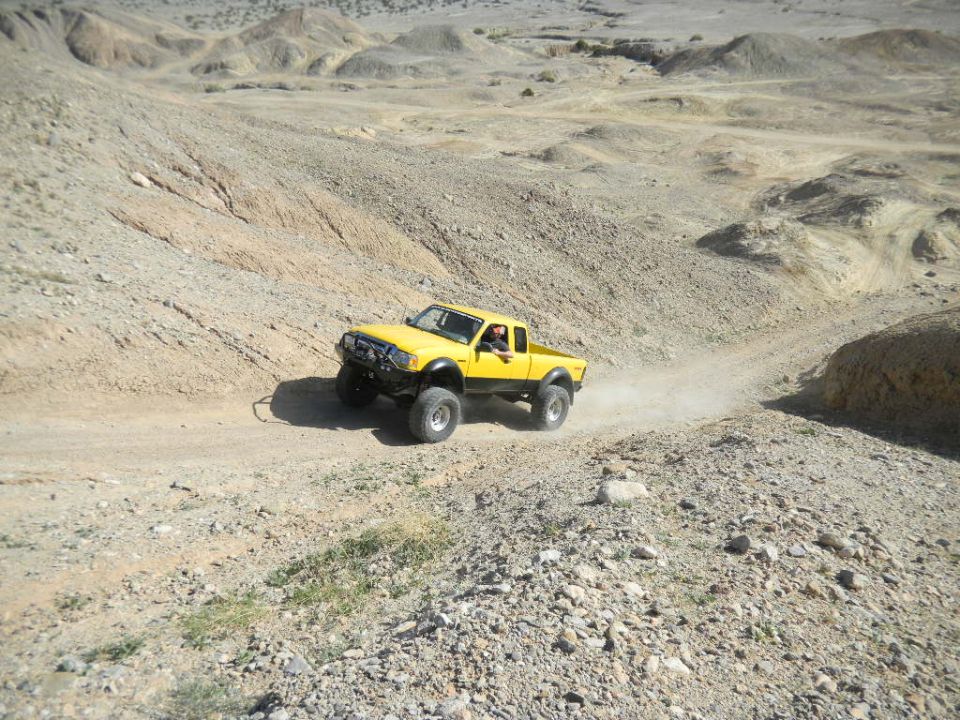 1997 Ford Ranger modified for off-roading, driving on a dusty desert trail