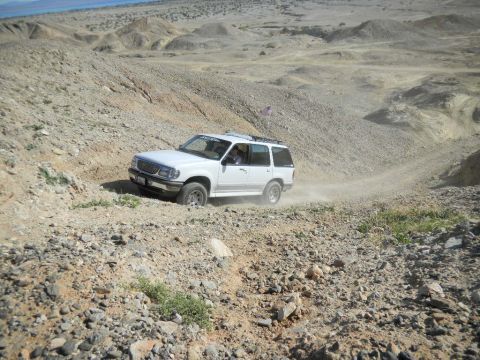 1997 Ford Ranger - A white 1997 Ford Ranger navigates a challenging off-road path in a desert landscape.