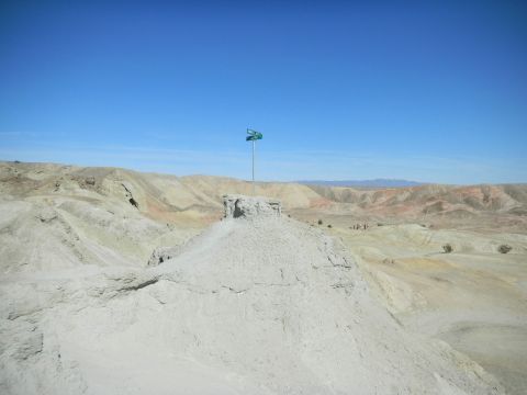 1997 Ford Ranger - A flag flies atop a rock formation in a vast desert landscape under a clear blue sky.