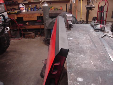 1989 Ford Bronco - A red vehicle door is secured in a vise on a metal workbench, ready for repair or modification.