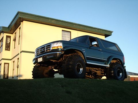 1996 Ford Bronco - This modified 1996 Ford Bronco sits high on a grassy incline under a clear blue sky.