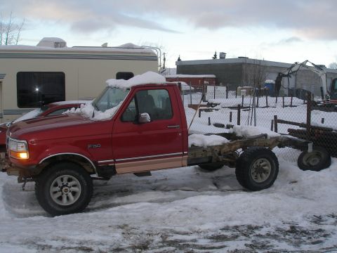 2001 Ford F-350 - A red pickup truck chassis sits in the snow, with an RV parked nearby. The truck appears to be a 1992 model.