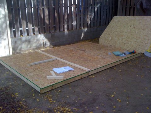 1968 Ford Mustang - A construction site shows a plywood floor being assembled with lumber and tools nearby.