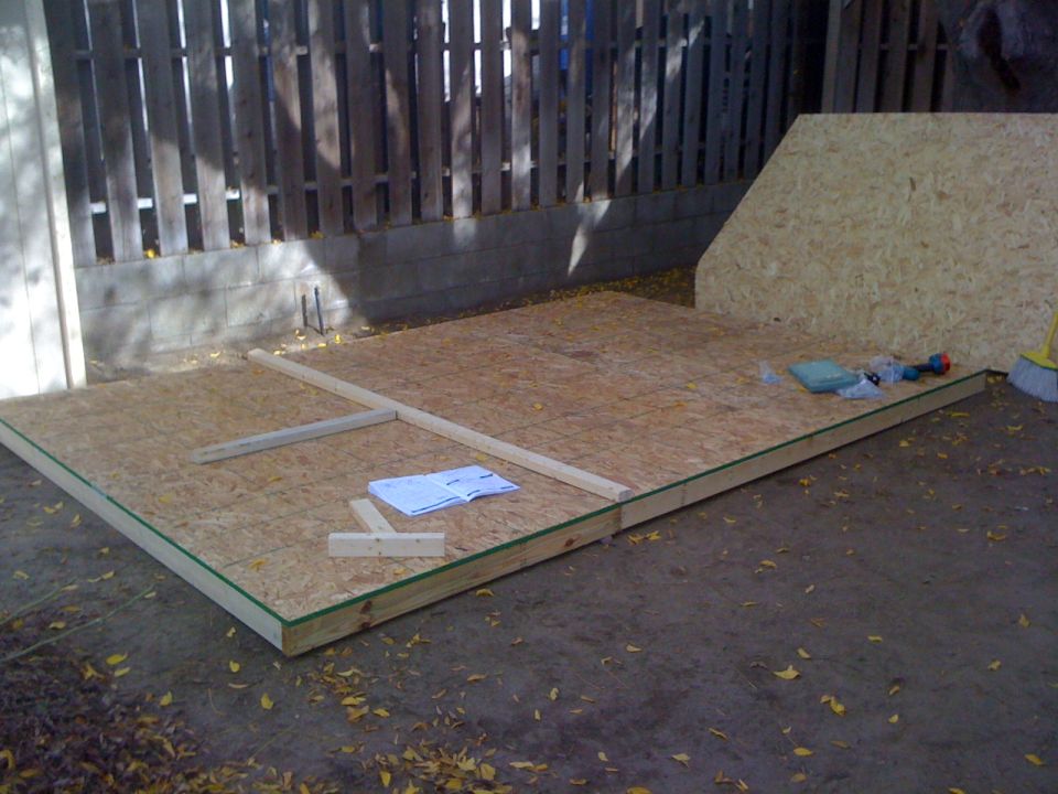 Construction site with plywood floor and lumber framing, tools, and instructions on the ground