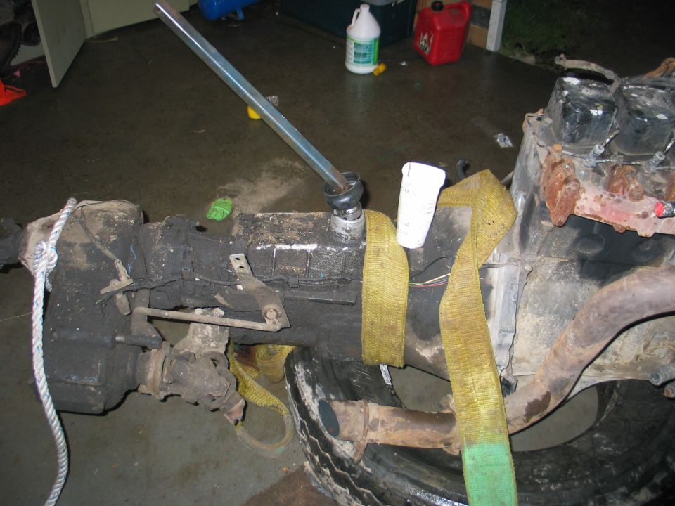 Engine block and transmission assembly with yellow straps, metal shaft, and tire